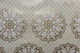 A close-up of a repeating damask-style wallpaper in warm beige, white, and metallic gold, with small white polka dots across a light beige background.