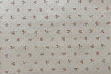 A close-up of a wallpaper pattern featuring a repeating small floral motif in muted red and brown on a warm off-white background.