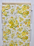 A vintage floral wallpaper hanging on a white paneled wall. The design features a dense pattern of yellow and green flowers on an off-white background.